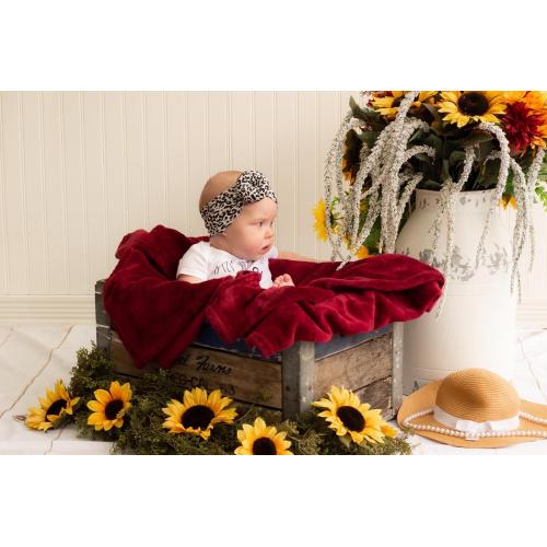 A baby wearing a Tiny Knot Co Lola, Black - Bamboo Baby Knotted Headwrap with sunflowers.