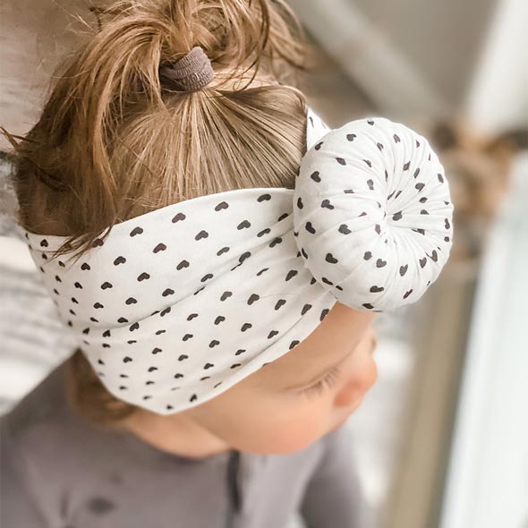 A little girl wearing a Tiny Knot Co headband with a polka dot pattern.