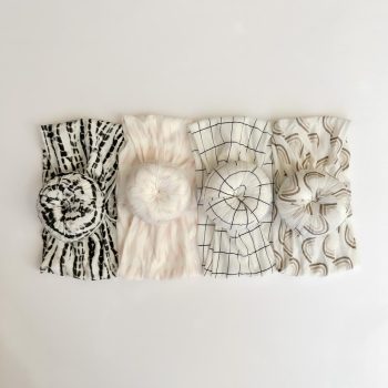 Four headbands with pom poms showcased on a white surface by Tiny Knot Co.