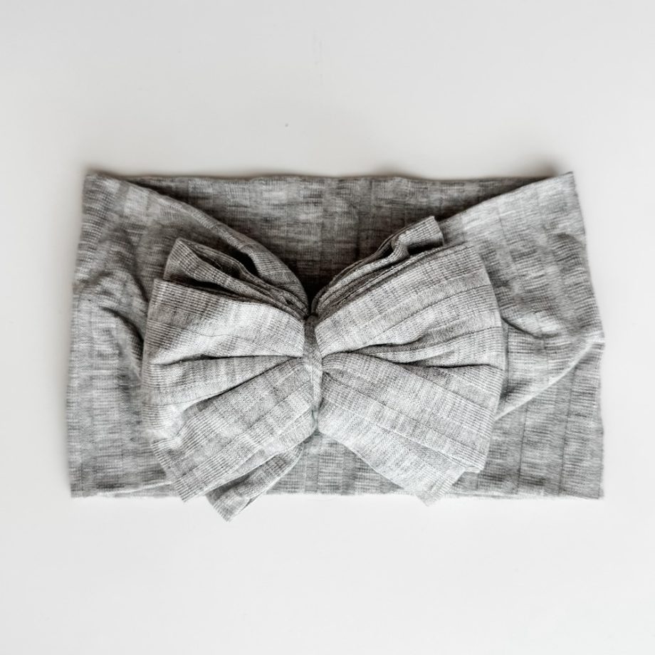 A grey bow headband on a white surface.