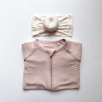 A pink shirt with a matching headband from Tiny Knot Co on a white surface.