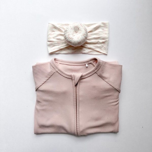 A pink shirt with a matching headband from Tiny Knot Co on a white surface.