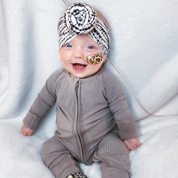 A tiny baby sporting a zebra-print headband from Tiny Knot Co.